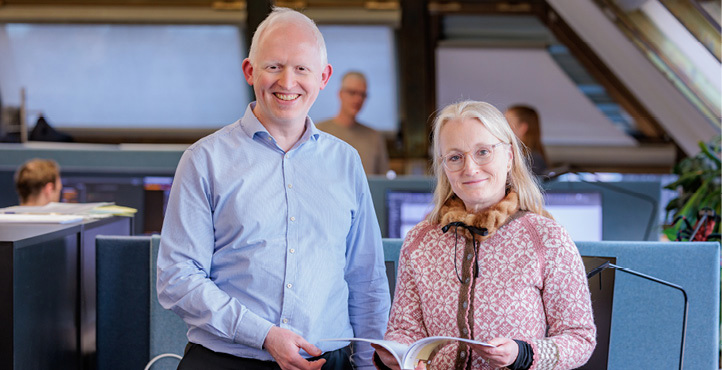 A male and a female employee standing and holding a report in their hands
