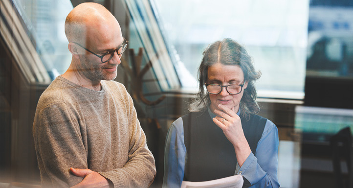 A male and female employee standing and looking at a printout