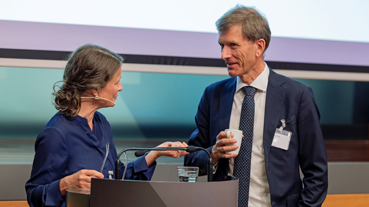 Anna Grinaker and Torbjørn Hægeland standing in conversation at a lectern