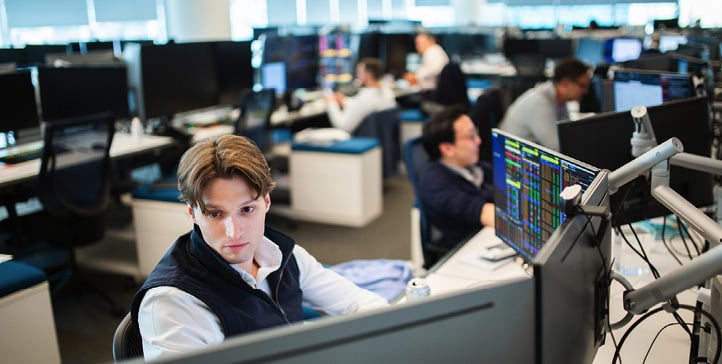 Men in front of computer screens in an open office landscape