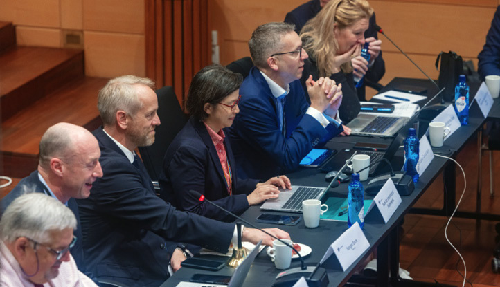 Delegater sittende ved panelbord