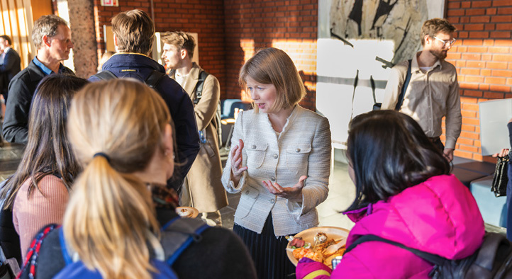 Ida Wolden Bache stående i samtale med studenter