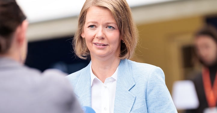 Woman standing, being interviewed by a man holding a microphone