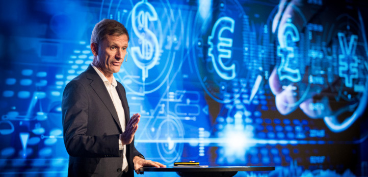 Man standing at a podium with a cryptocurrency illustration in the background