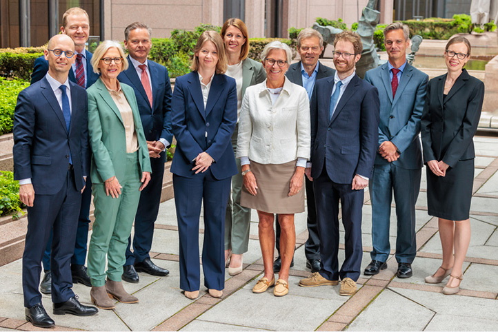 Group photo of 11 persons (6 men and 5 women) standing in a courtyard at Norges Bank