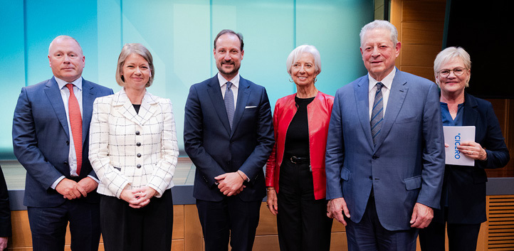 Three men and three women standing in front of a stage