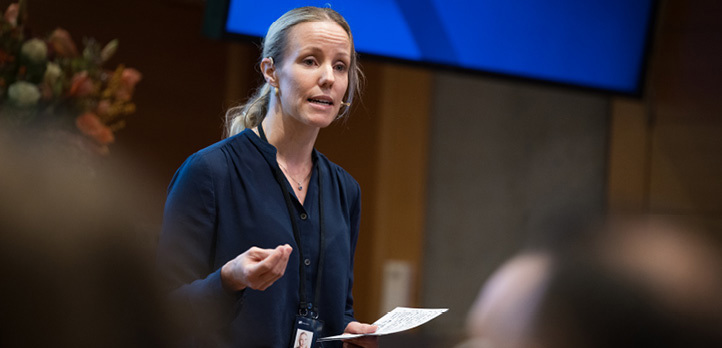 A woman wearing a headset with microphone holding a sheet of paper 