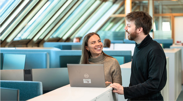 Smiling man and woman standing behind an open laptop computer