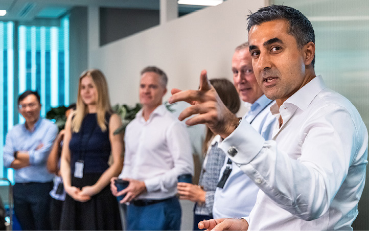 Man in the foreground pointing and explaining to a small group pf people behind him 