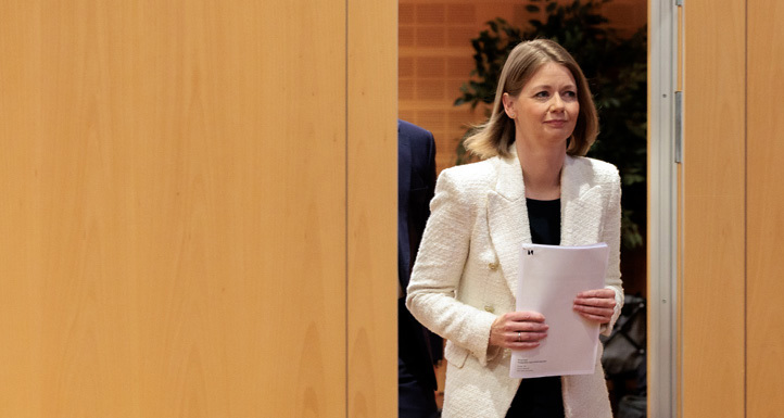 Kvinne kommer ut fra en åpnet dør med papirer i hendene