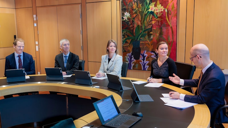 The five members of the committee sitting by a meeting table